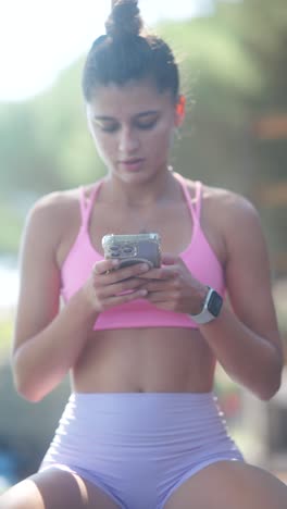 young woman in activewear using smartphone outdoors