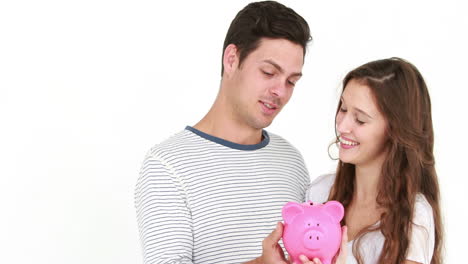 una pareja sonriente con una caja de ahorros.