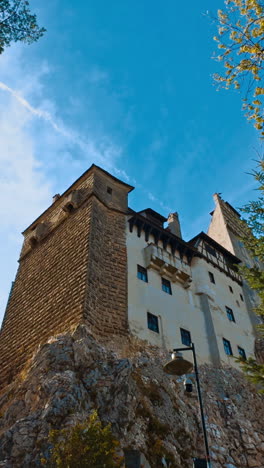 high rocks with forest and castle on the top. bran castle in brasov, romania. low angle view. vertical video