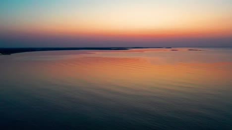 colorful ocean sunset in saco, maine with bright colors reflecting off calm rippling sea waves along the new england atlantic coastline