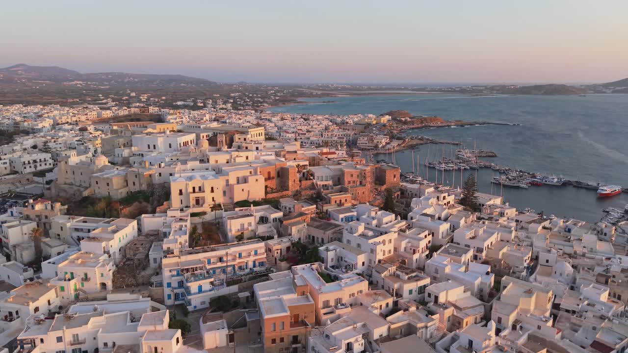 A smooth drone orbit around the castle in Chora Naxos, unveiling panoramic views of the bustling port and beautiful seafront along the Aegean coast