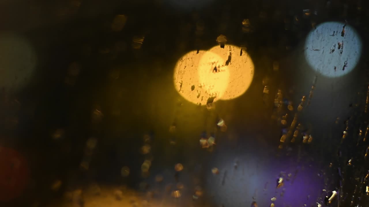 보케 조명 배경으로 더러운 창문에 밤의 비가 떨어집니다.