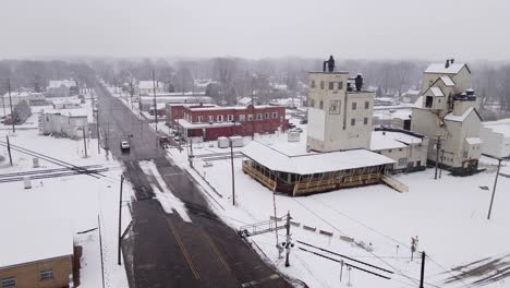 Industrial-buildings-of-small-USA-town-covered-in-snow,-aerial-orbit-view