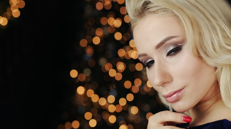 Ritratto di una giovane donna attraente sullo sfondo di luci sfocate di decorazioni natalizie 2