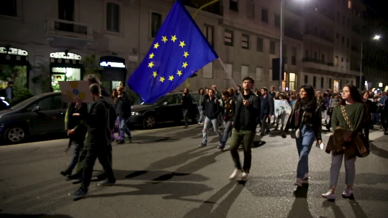 Global Strike for Climate Change. European flag in the middle of thousands of people attending streets in Milan by night. Friday for future with Greta Thunberg