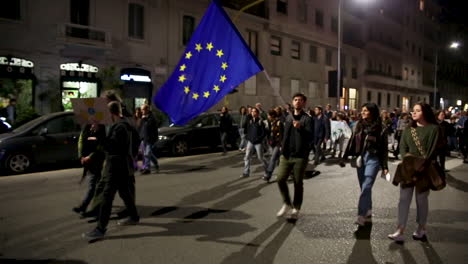 global strike for climate change. european flag in the middle of thousands of people attending streets in milan by night. friday for future with greta thunberg