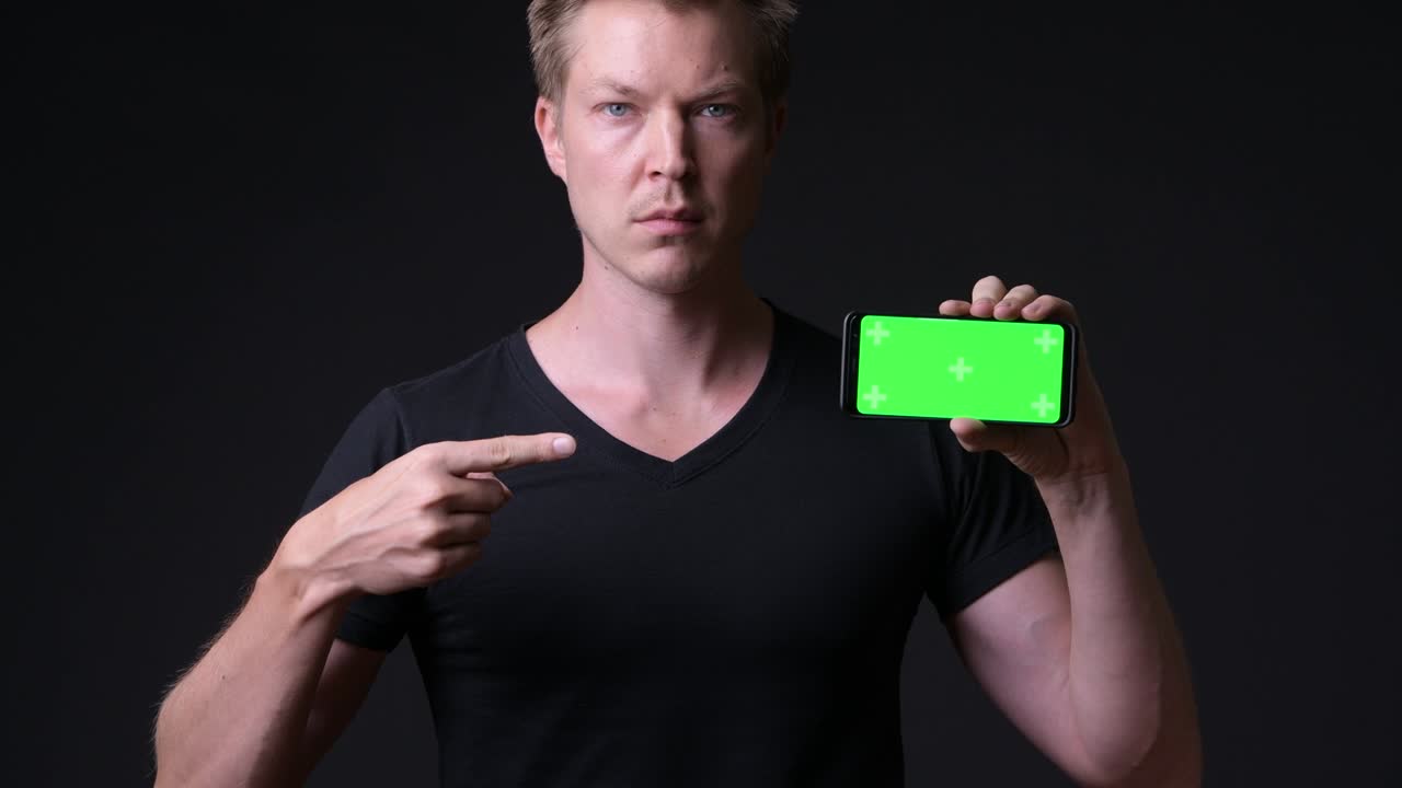 hombre sosteniendo un teléfono móvil con pantalla verde de clave de croma