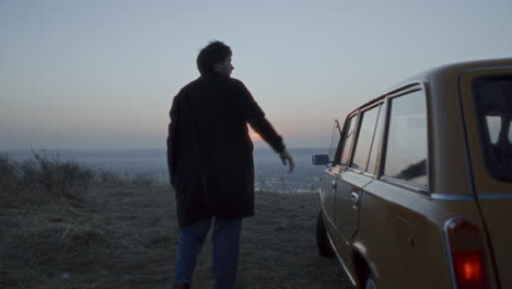 couple leaving car, walking toward frozen lake and looking at sunset