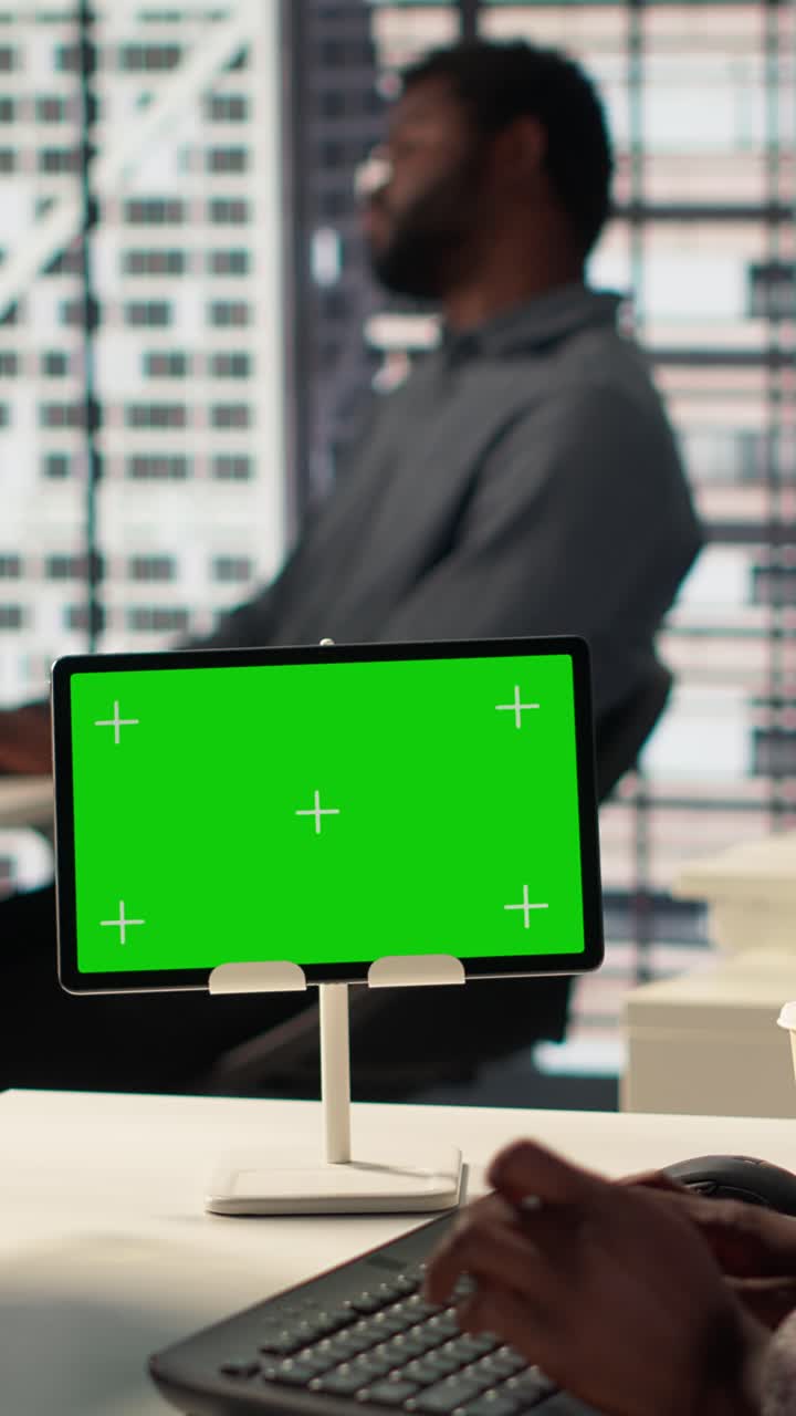 Person Typing on Keyboard with Green Screen Tablet in Modern Office