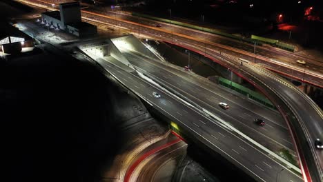 aerial flyover traffic jam interchange road at night, drone shot top down view roadway intersection in modern city in evening. lot of cars driving busy junction highway in fast motion