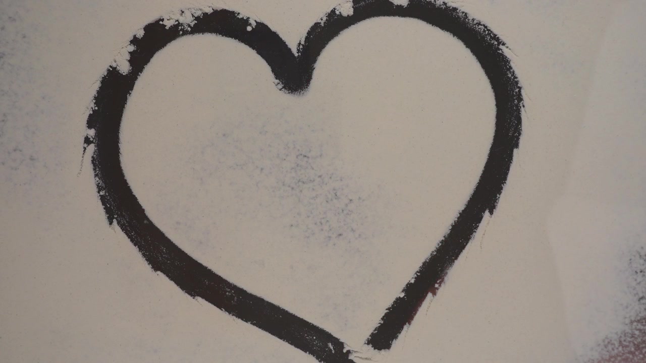 Drawing of a heart on a glass surface against a flour background. Bottom view.