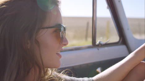 beautiful girl taking photos with smart phone on road trip in convertible vintage car