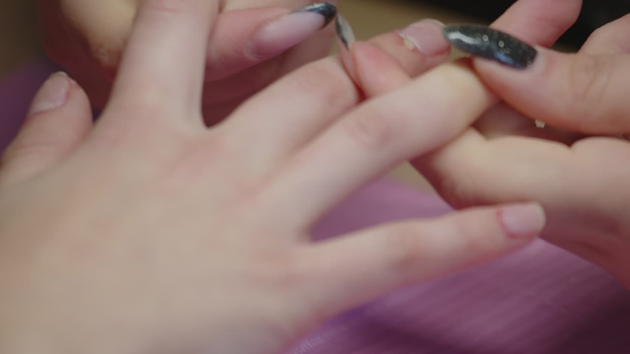 A manicurist massaging her client's fingers during a beauty service on her hands, close up