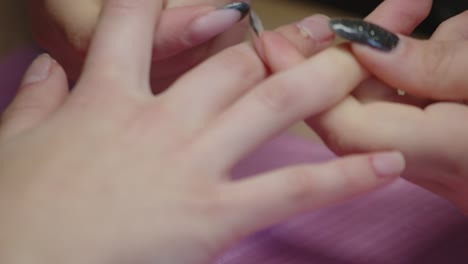 a manicurist massaging her client's fingers during a beauty service on her hands, close up