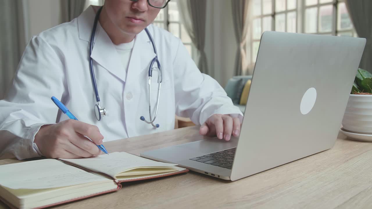 Doctor working on laptop and writing notes