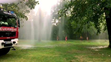 camión de bomberos alemán rociando agua para niños y árboles en un caluroso día de verano-5