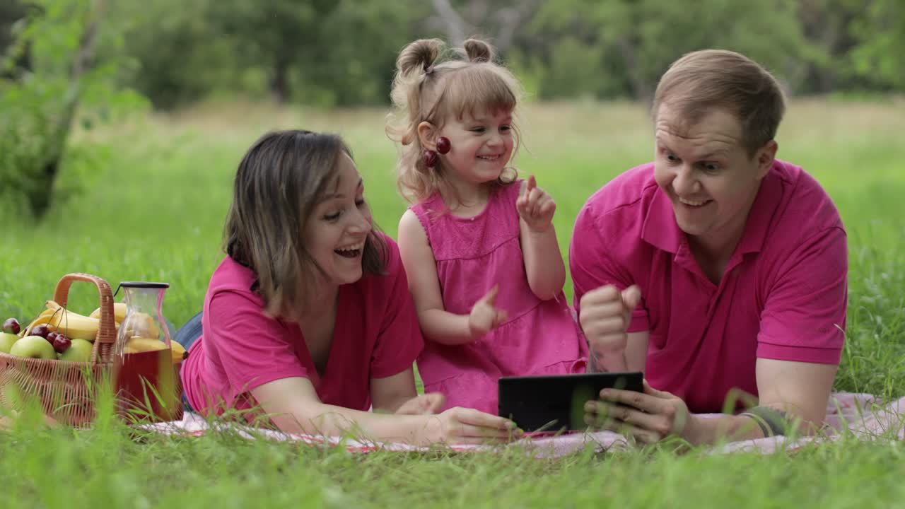 Family weekend picnic. Daughter child girl with mother and father celebrate success online shopping