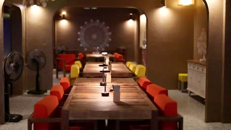 warmly lit empty restaurant with colorful chairs and wooden tables