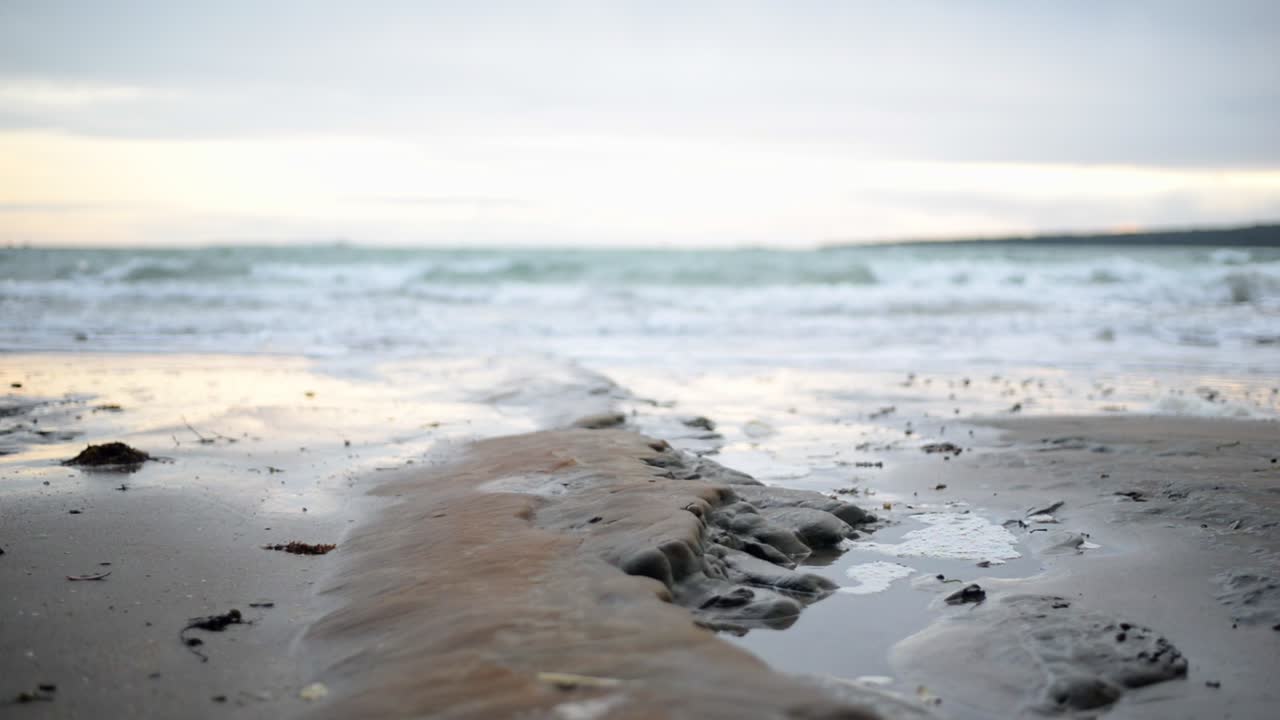 Glatte steinformasjoner i sanden på en østkyststrand på New Zealand.