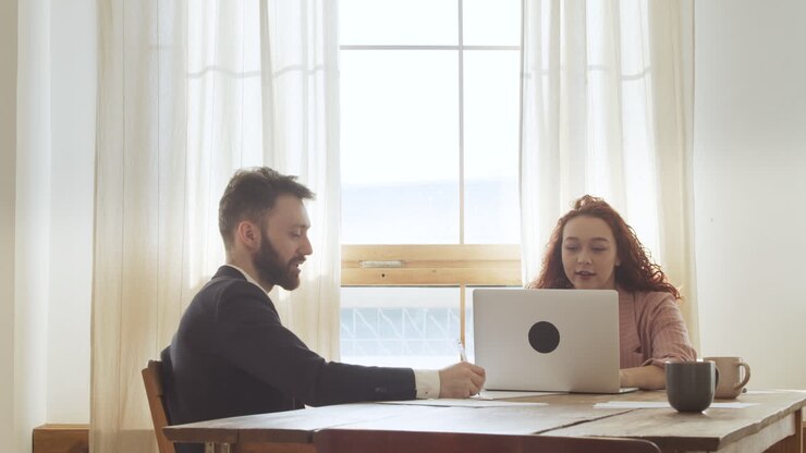 Zwei Kollegen diskutieren, am Tisch im Büro sitzend