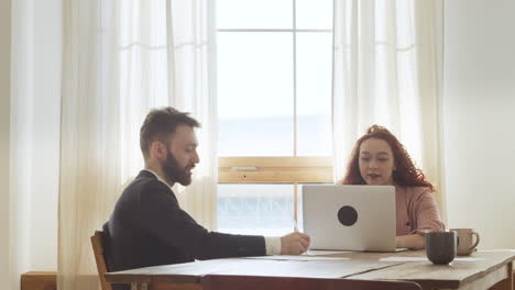 two colleagues debating sitting at table in the office