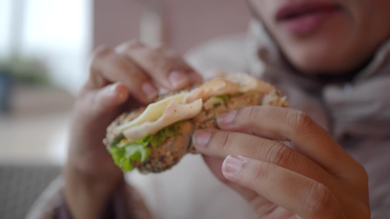 mujer comiendo un sándwich de pavo y lechuga