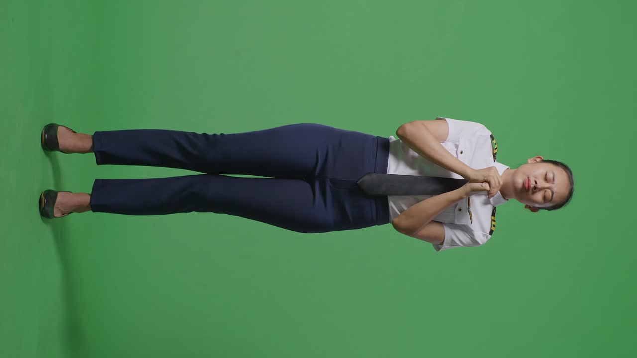 녹색 스크린 배경 스튜디오에 서 있는 동안 무언가를 위해 기도하는 아시아 여성 조종사의 몸이 가득 차 있습니다.