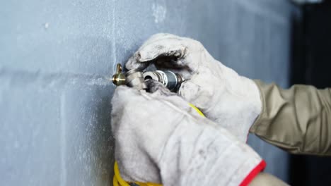 Hands-of-mechanic-connecting-a-wire-to-spray-nozzle