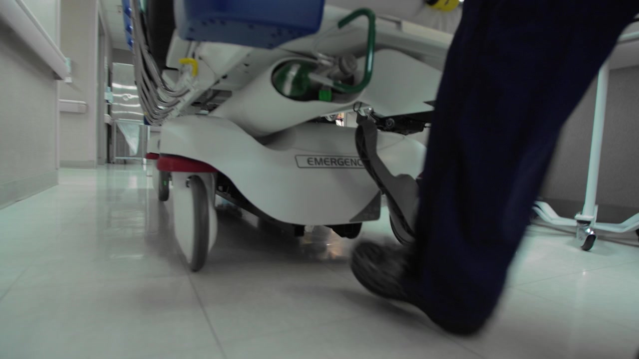 Carrellata ad angolazione estremamente bassa delle ruote di una barella d'emergenza ospedaliera - (4K UHD).