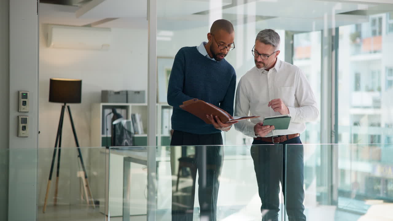 Two Businessmen Discussing Documents and Digital Information in Modern Office