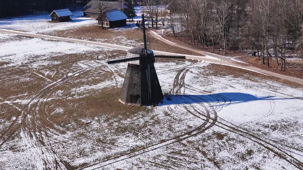 Beautiful wooden mill on snowy fields, aerial orbit view