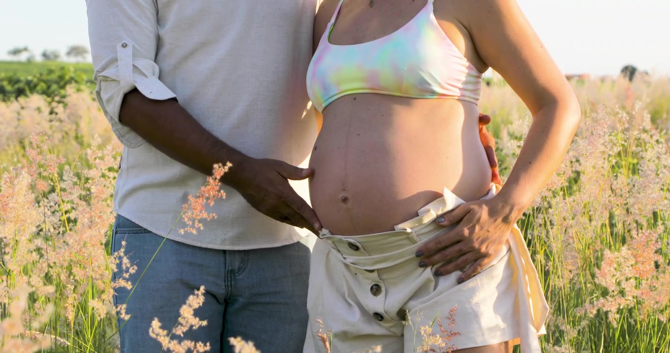 Neo papà che passeggiano nella campagna fiorita per rilassarsi e aspettare il bambino.