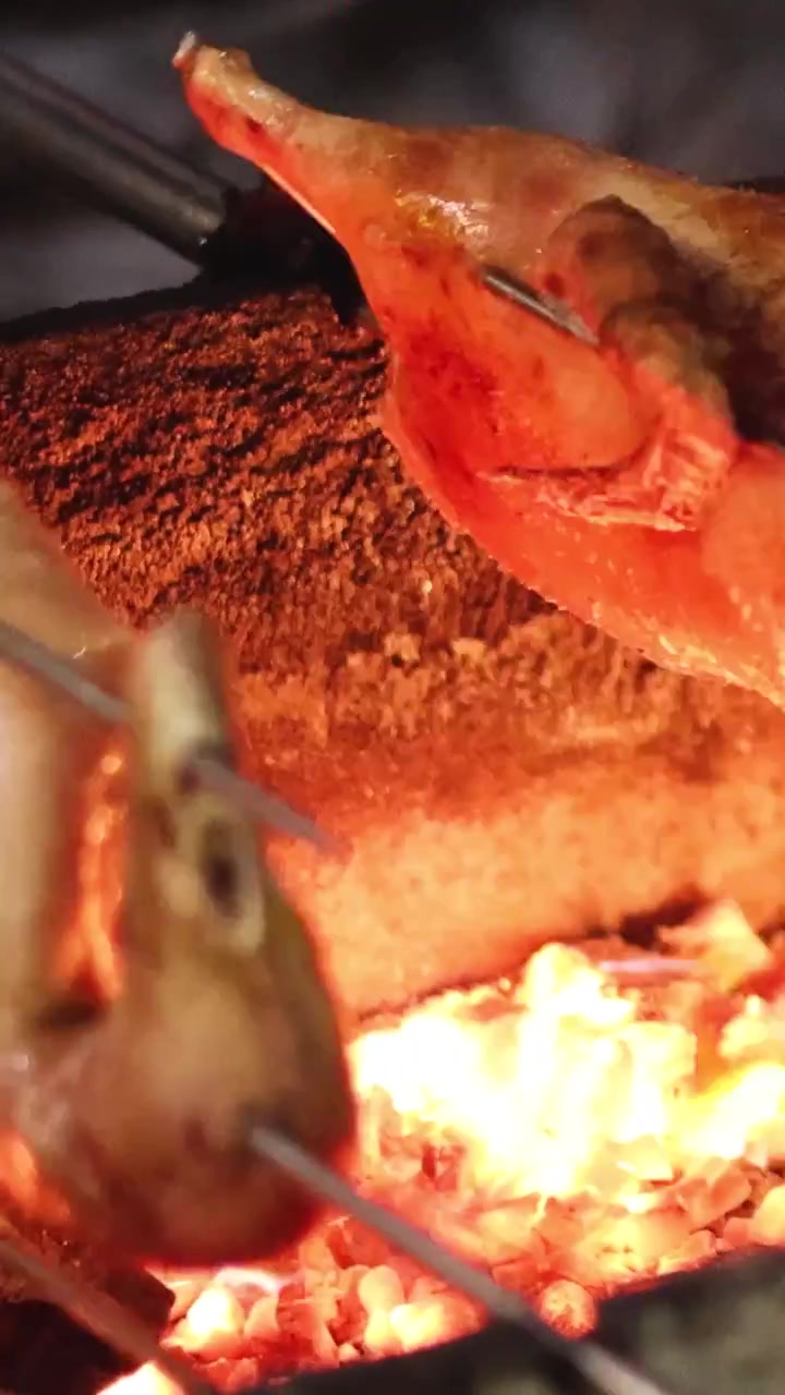 炎の上で串焼きにされているアヒルたち