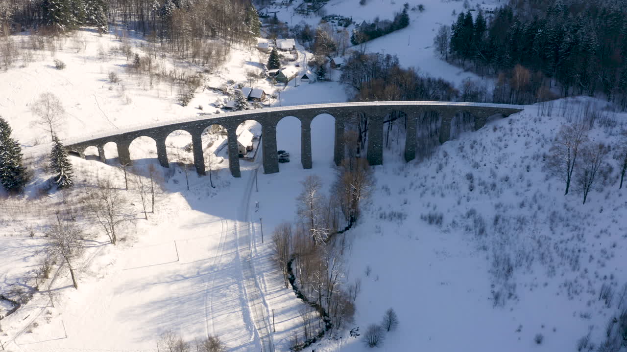 겨울의 강 계곡 위의 돌기차 고가교, 눈이 내리는 시골