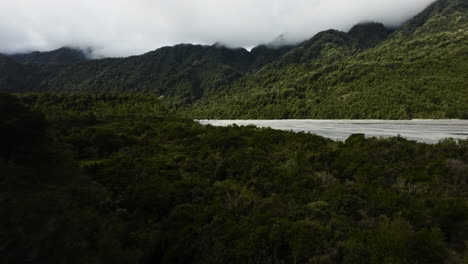 fpv acrobático que revela una toma de un arroyo que corre en el valle de la montaña en nueva zelanda