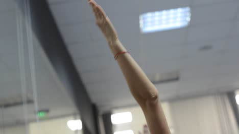 Attractive-young-female-yoga-teacher-demonstrates-exercises-to-group-class-abstract-camera-movement