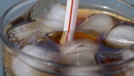 Macro-En-Cámara-Lenta,-Dejando-Caer-Una-Pajita-De-Plástico-En-Un-Refresco-Helado