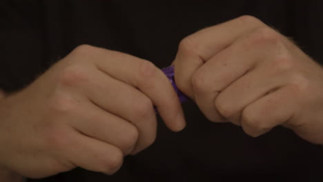 male hands struggling to open purple condom package