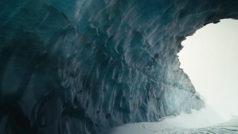 View-through-giant-blue-ice-cave-and-abstract-icy-formations-slow-pan