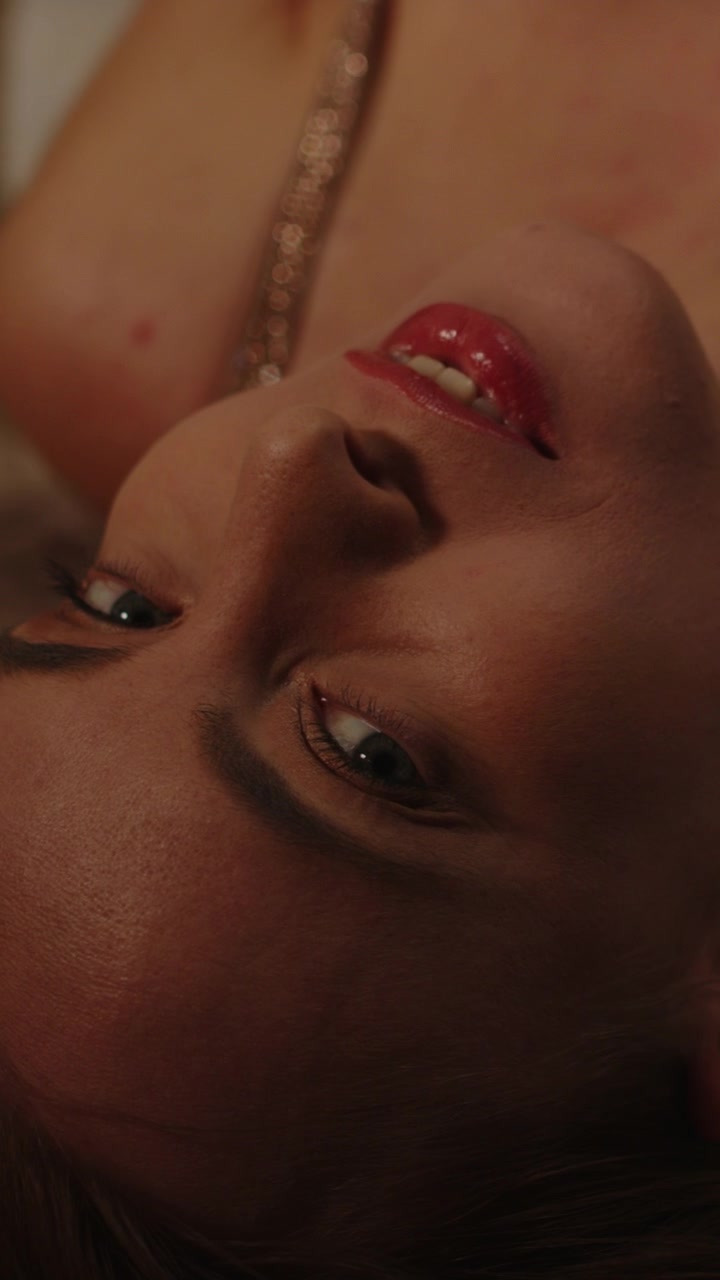 Beautiful vertical close up of an attractive woman wearing a sparkling brassiere lying on a fur rug on the floor