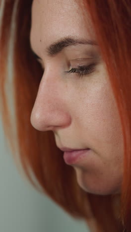 curious redhead woman looks at bacteria through modern microscope. young female scientist does professional research in laboratory close view