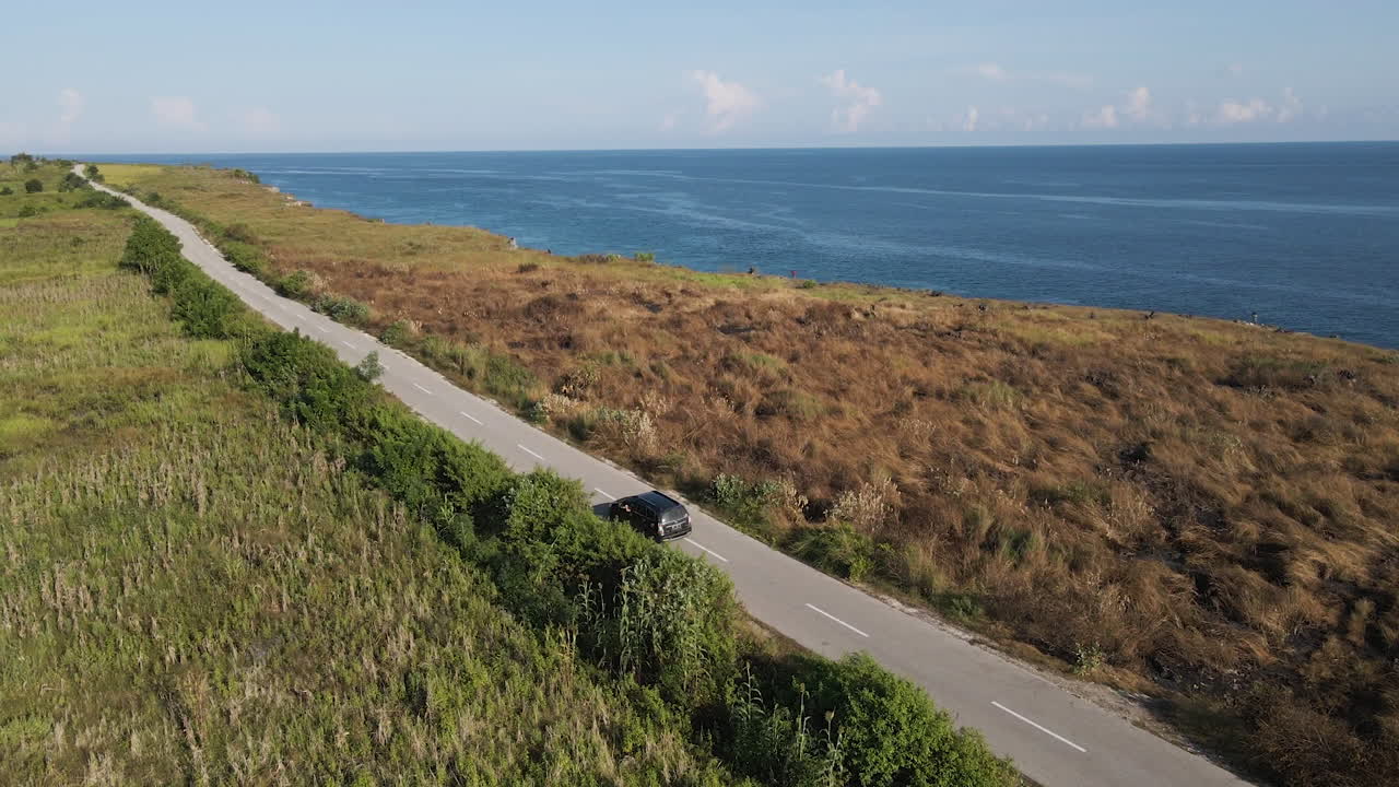 coche conduciendo por la carretera vacía con vistas al mar azul en la isla de sumba, indonesia