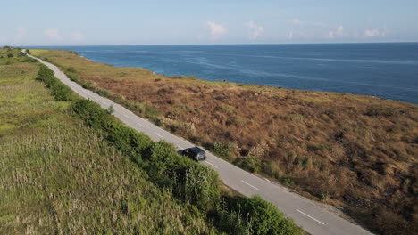 Coche-Conduciendo-Por-La-Carretera-Vacía-Con-Vistas-Al-Mar-Azul-En-La-Isla-De-Sumba,-Indonesia