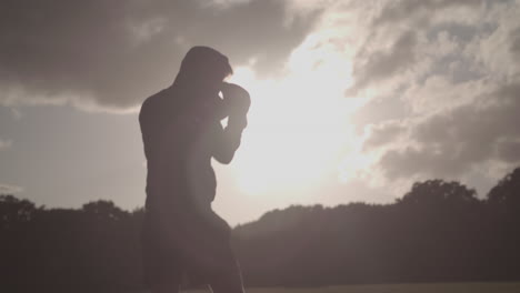 joven boxeo de sombra en las noches de verano en el parque