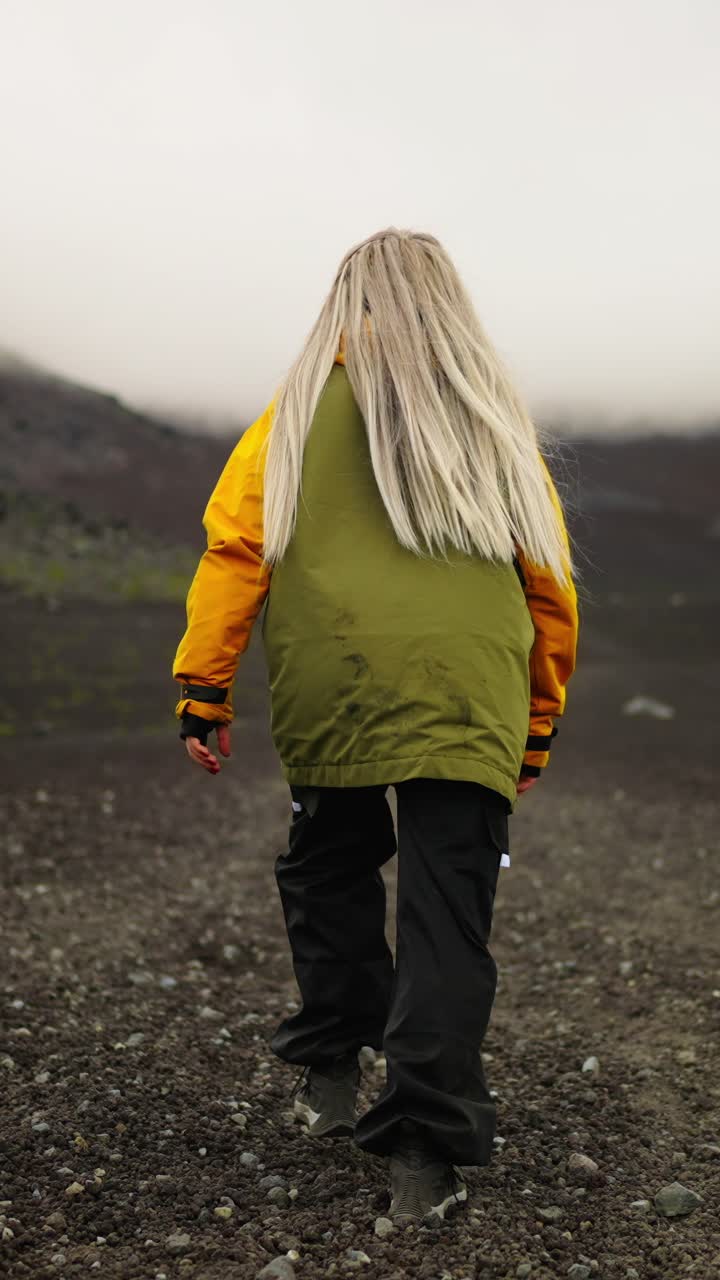 Femme marchant sur un paysage volcanique rocheux dans le brouillard