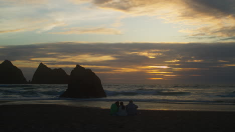 hermosa puesta de sol con turistas de vacaciones en la orilla arenosa de la playa de la bahía de holywell en cornwall, inglaterra