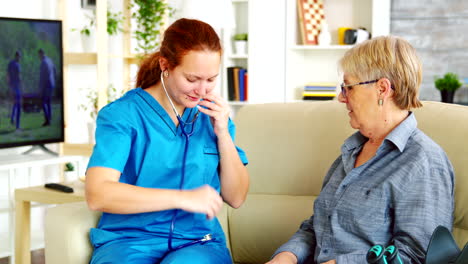 caucasian female doctor in nursing home listening old woman heartbeat