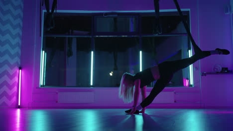 una mujer adulta está haciendo ejercicios de estiramiento con hamaca en la clase de yoga tipo moderno de acondicionamiento físico