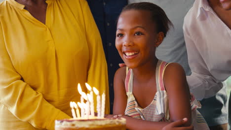 Multi-Generation-Family-Celebrating-Granddaughter's-Birthday-With-Cake-And-Candles-At-Home