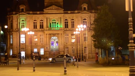 brightly lit colourful stone building in town square at night